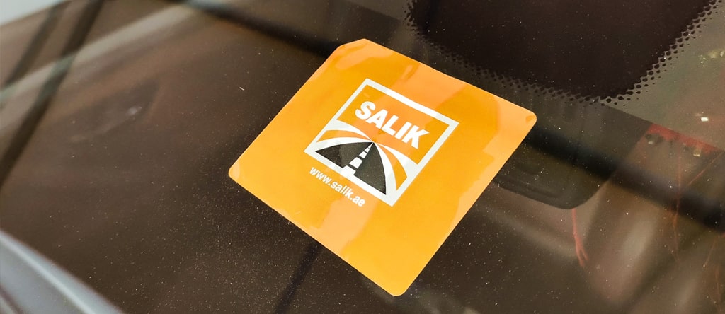 Yellow color salik slip sticker on the car glass, road design in the middle of the sticker also website details mentioned 